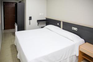 a bedroom with a white bed and a desk at Rede Andrade Vivaldi in Foz do Iguaçu