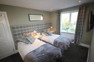 2 camas en una habitación con ventana en The Sunningdale en Bamburgh