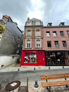 un edificio rojo con una mesa y sillas delante de él en Le Loft du Homard Bleu - entre Ciel et Mer - Free Parking 500m, en Honfleur