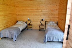 two beds in a room with wooden walls at "Cztery Klony" in Kowale Oleckie
