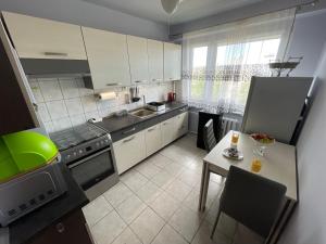 a kitchen with white cabinets and a table with a table at Apartament Regina in Ustka