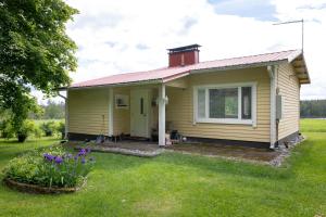 Mummon mökki - Granny´s cottage في Suonenjoki: منزل أصفر صغير مع ساحة عشب