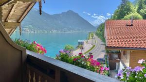 balkon z kwiatami i widokiem na jezioro w obiekcie Fewo am See w mieście Pertisau