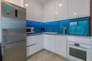 eine Küche mit weißen Schränken und blauen Wänden in der Unterkunft MB APARTMANI in Crikvenica