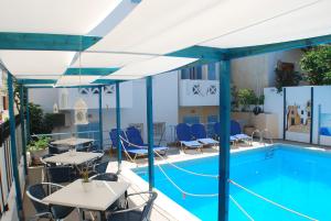 una piscina en la azotea de un hotel con mesas y sillas en Super economy studio short distance from the beach, en Agia Pelagia