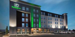 a hotel building with a green lit sign on it at Holiday Inn Greenville - Woodruff Road by IHG in Greenville