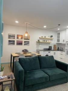 uma sala de estar com um sofá verde e uma cozinha em Casa dos Palecos na Nazaré