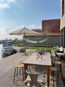 a patio with a table and chairs and an umbrella at Boot & Huis Heeg in Heeg