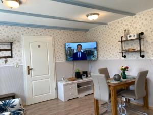 uma sala de estar com uma mesa e uma televisão na parede em Gästehaus Daheim em Lohme
