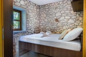 a bedroom with a stone wall with a bed at Stone House in Lovinac +25 photos