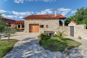 a stone house with a garage and a driveway at Stone House in Lovinac