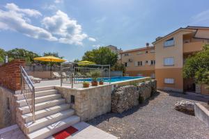 a swimming pool with stairs and an umbrella next to a building at Apartmani Jarić in Novi Vinodolski