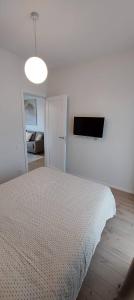 a white bedroom with a bed and a light at Apartamentai AQUA in Palanga