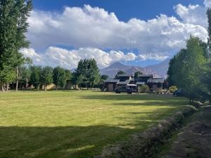 un gran campo de césped con una casa en el fondo en Cabañas Los 4 elementos - Uspallata en Las Heras