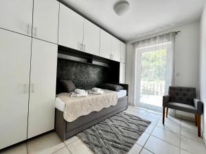 a bedroom with a bed with white cabinets and a window at Apartments Lokunja in Pag