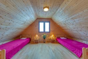 2 łóżka w drewnianym pokoju z różową pościelą w obiekcie Zagroda Bukowiec w Polańczyku