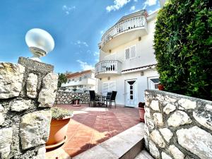 a house with a stone wall and a patio at Apartments Lokunja in Pag