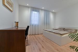 a bedroom with a bed and a desk and a window at Beautiful modern apartment with large livingroom in Bihać