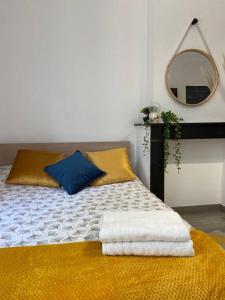 1 cama con almohadas amarillas y azules y espejo en Le Petit Gayant, en Douai