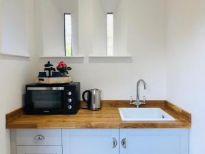 a kitchen counter with a microwave and a sink at The Outhouse - Cosy Country Guest Suite in Kingston