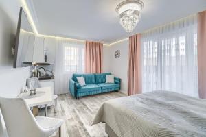 - une chambre avec un lit bleu et un canapé dans l'établissement Silver Apartments, à Świnoujście