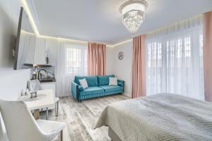 a bedroom with a blue bed and a couch at Silver Apartments in Świnoujście