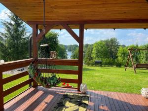 una hamaca en una terraza con vistas a un parque en Domek z kominkiem nad jeziorem z jacuzzi ogrodowym, en Sumowo