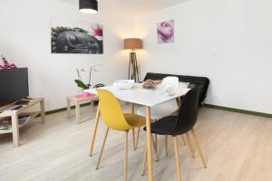 a dining room with a white table and yellow chairs at Appartement cocooning avec vue sur les Pyrénées in Argelès-Gazost
