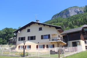 a building with a fence in front of a mountain at Chez Gilles et Christine in Mieussy