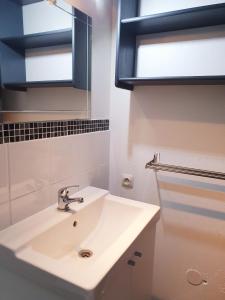 a white bathroom with a sink and a mirror at Appartement climatisé à deux pas de la plage in Port Leucate