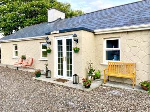 uma pequena casa com um banco à frente em Lemonade Cottages and Retreat em Kilrush