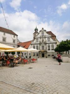 un gran edificio blanco con mesas y sillas delante de él en B&B Ferienwohnung in bester Lage, en Wangen im Allgäu