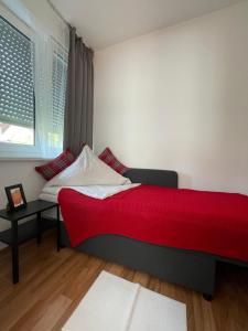 a bedroom with a red bed and a window at Rose No 4 in Friedrichshafen