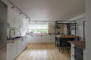 a kitchen with white cabinets and a wooden floor at Złota#208 in Złota