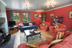 uma sala de estar com paredes vermelhas e mobiliário vermelho em The Press House em Carrbridge