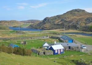 a small house in a field next to a body of water at Tigh Bhisa Blackhouse in Tolstachaolais