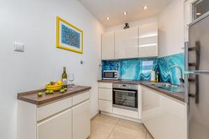 cocina con armarios blancos y pared de acento azul en Award winning Garden Apartment with large Terrace and amazing Seaview, en Bol