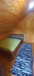 Cama en habitación de madera con alfombra en Crkvine Chalet, en Kolašin