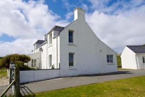 a white house with a fence in front of it at 7A Ardroil in Uig