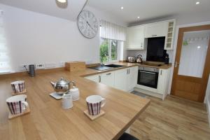 een keuken met een tafel en een klok aan de muur bij Tulloch House in Lochboisdale