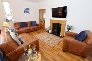 a living room with leather furniture and a fireplace at Tulloch House in Lochboisdale