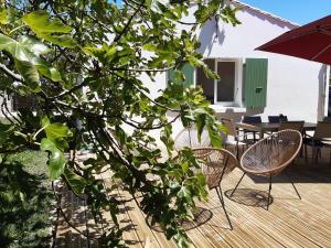 2 sillas y una sombrilla en una terraza de madera en Charmante maison de plain pied avec 700m2 de jardin cloturé en Saint-Clément-des-Baleines