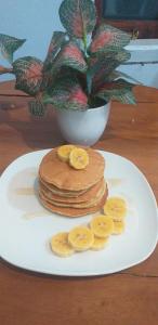 a plate with a stack of pancakes and sliced bananas at D'corner Homestay in Lumajang