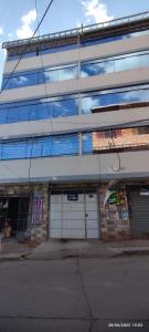 a tall building with two white garage doors and windows at Anacondor Guests House in Cusco