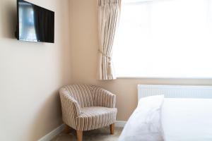 una camera da letto con una sedia e una televisione appesa a un muro di The Cedars a West Clandon