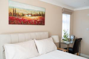 una camera da letto con un letto e un dipinto sul muro di The Cedars a West Clandon