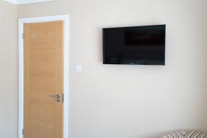 a flat screen tv on a wall next to a door at The Cedars in West Clandon +12 photos