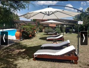 a group of lounges with an umbrella and a pool at Cabañas Thijada in Mina Clavero