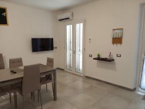 a dining room with a table and a television on the wall at La casa di Isa in Maracalagonis