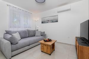 a living room with a gray couch and a table at Apartment Bellistra Rabac in Rabac